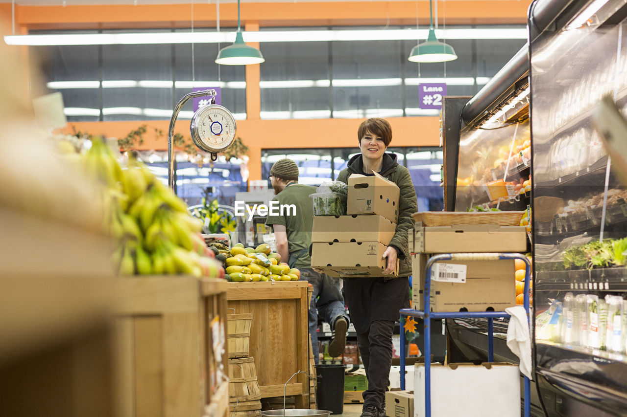 Female worker carrying boxes while working at supermarket