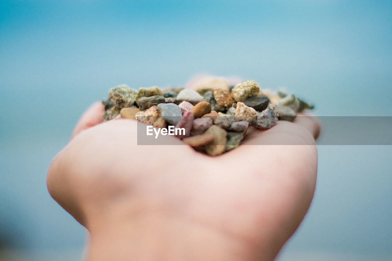 Cropped image of hand holding small stones