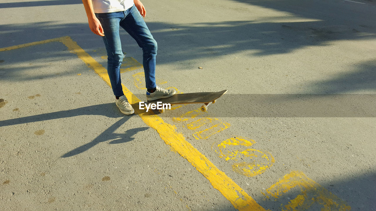 Low section of man skateboarding on road