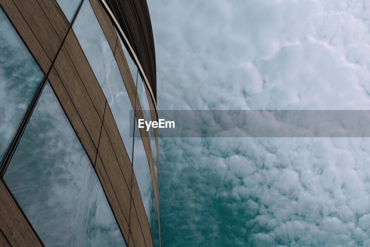 Low angle view of building against sky, sky reflected in windows