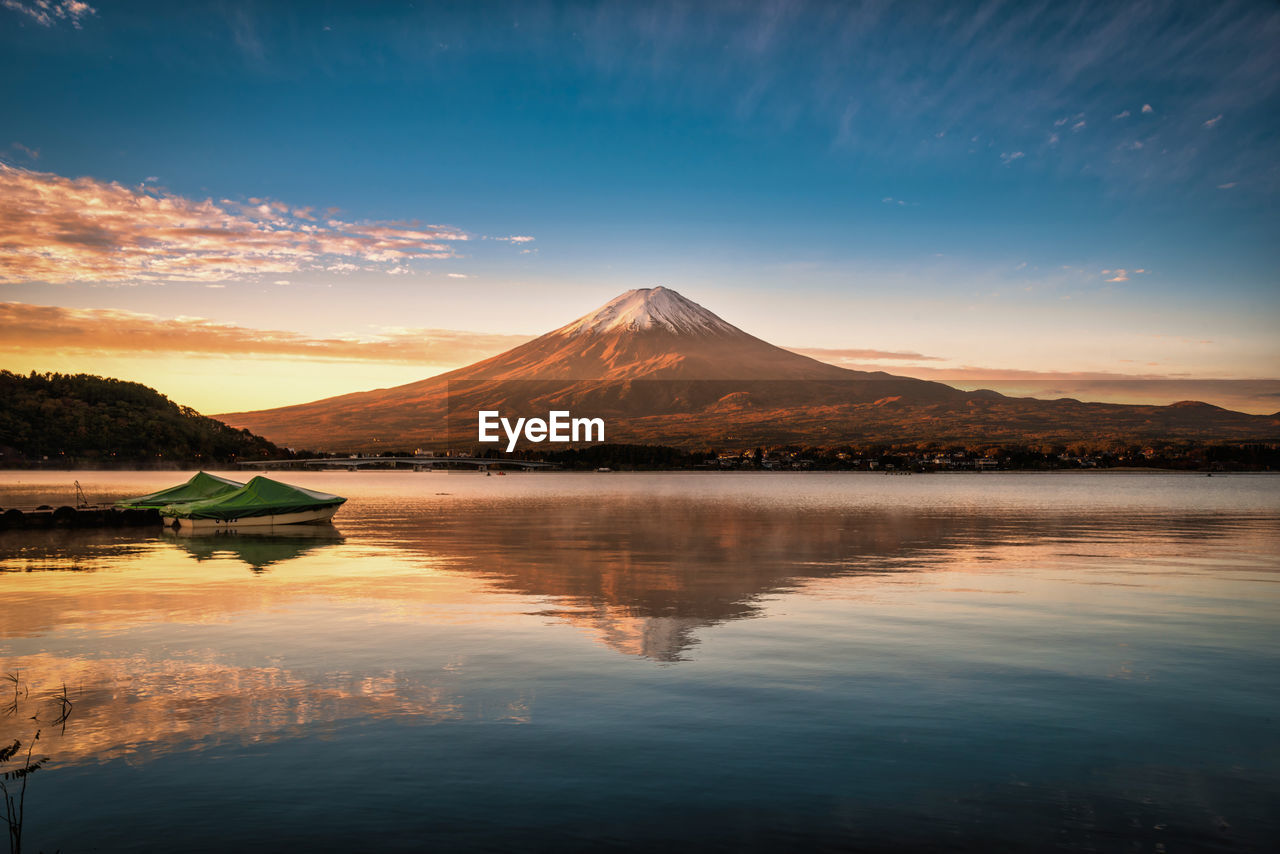 Scenic view of lake against cloudy sky during sunset