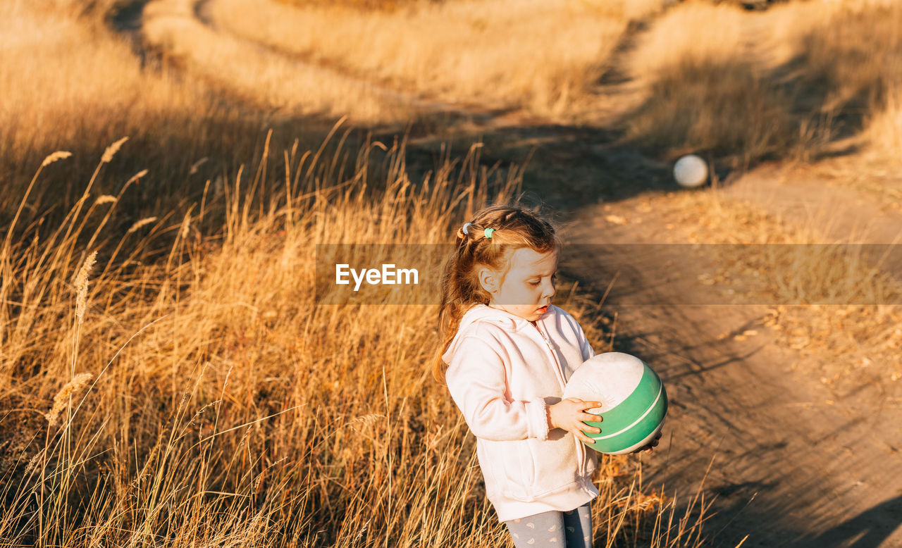 Cute little girl playing ball outdoors