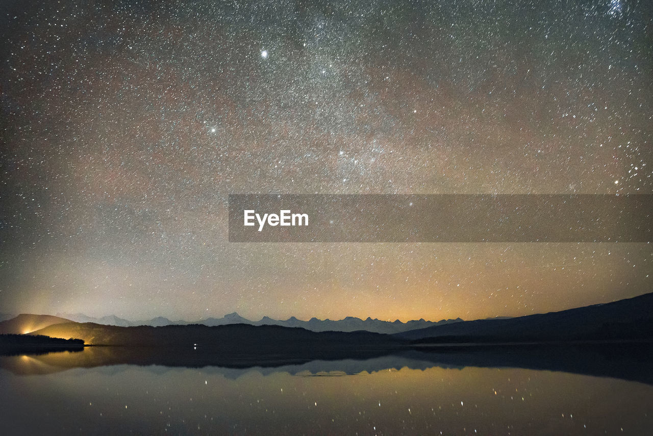 SCENIC VIEW OF LAKE AGAINST MOUNTAIN AT NIGHT