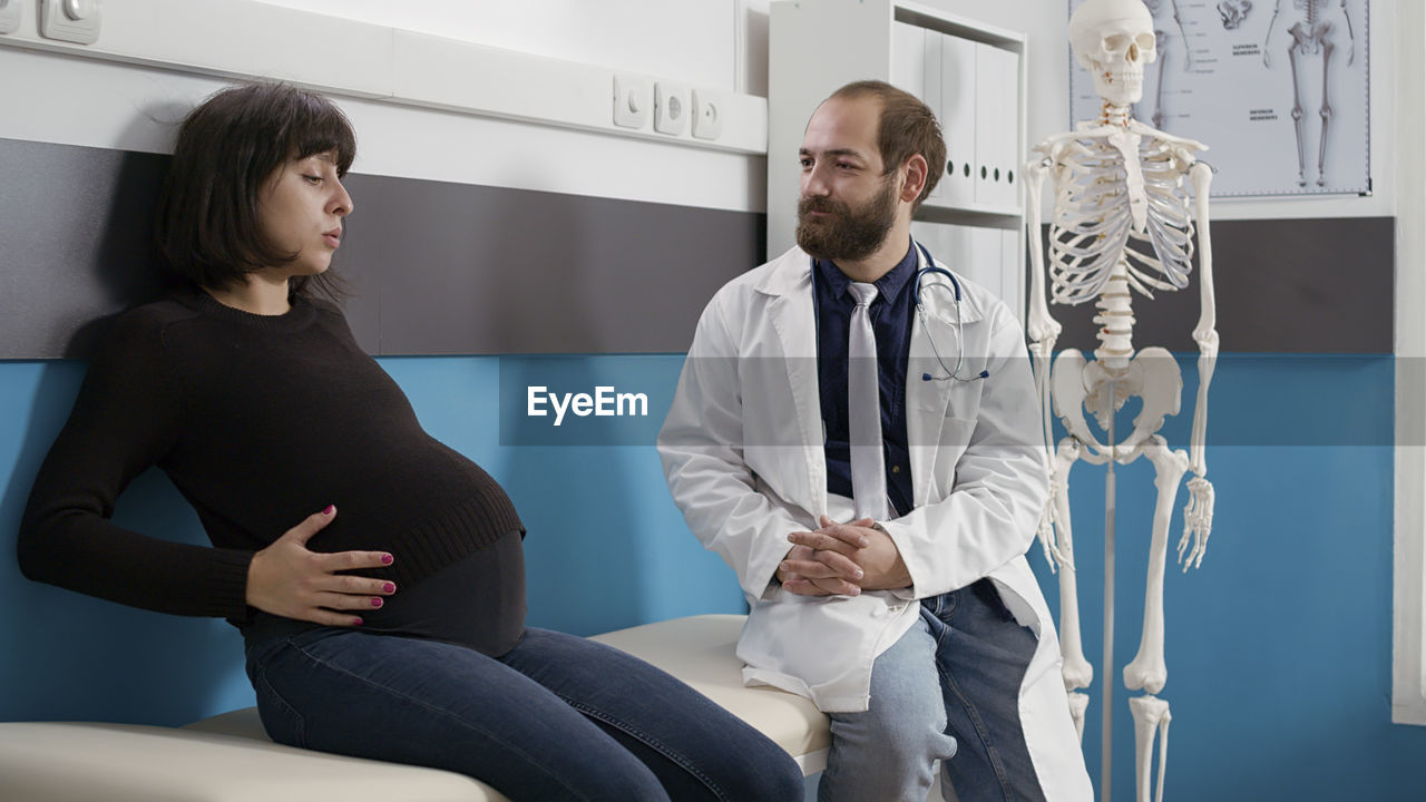 Pregnant woman sitting by doctor in hospital