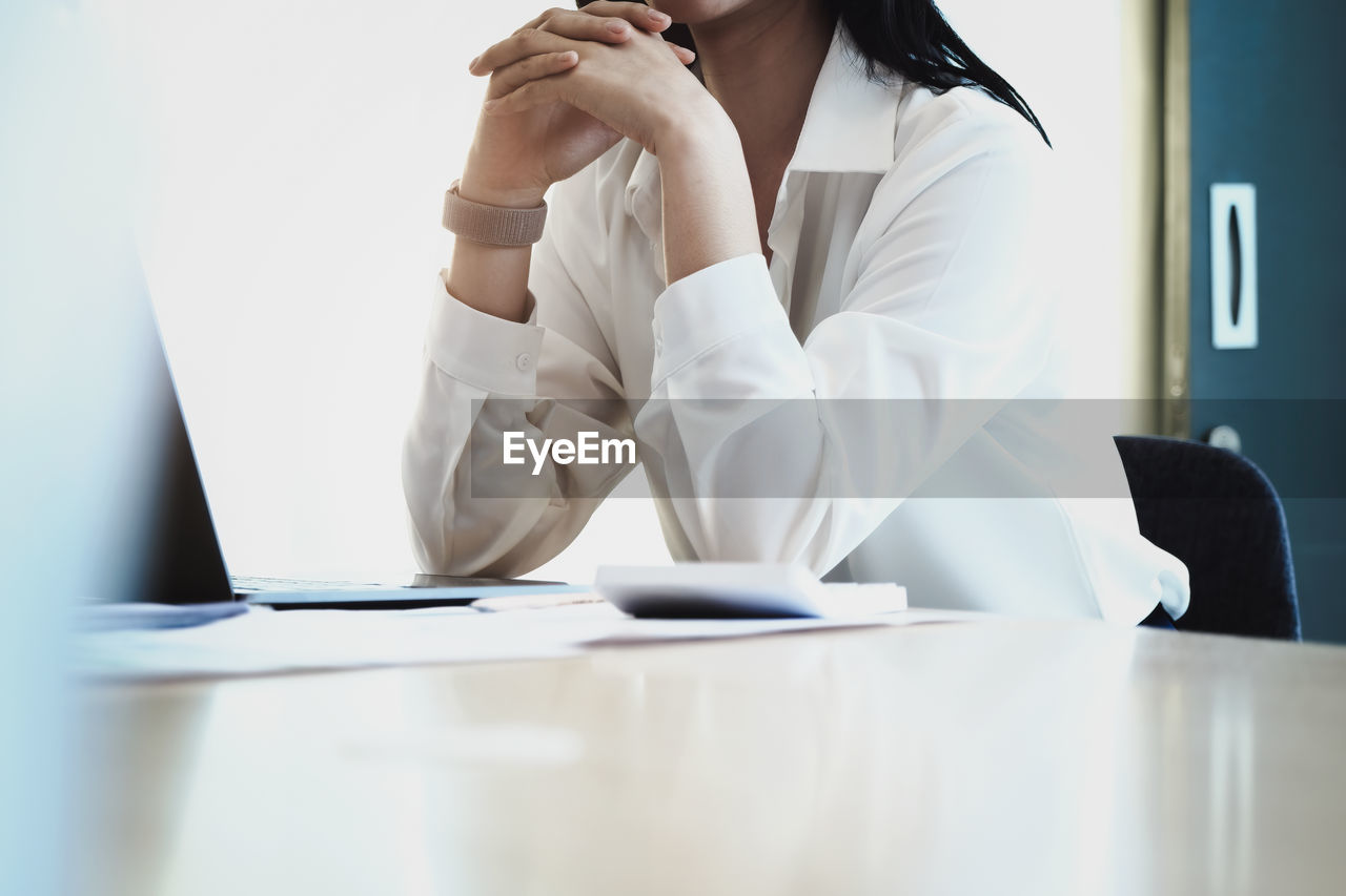 REAR VIEW OF WOMAN WORKING ON TABLE IN OFFICE