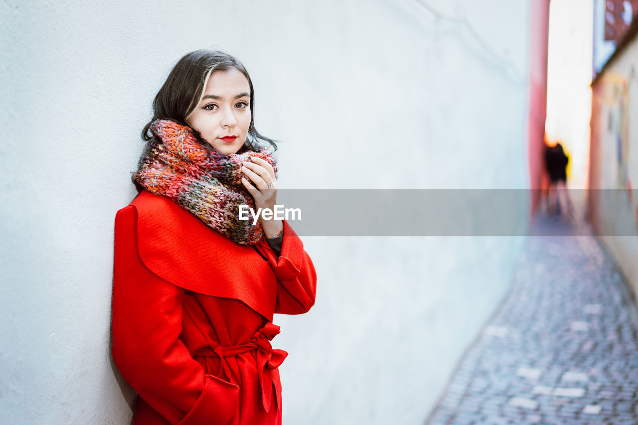 Portrait of young woman wearing warm clothing standing in alley