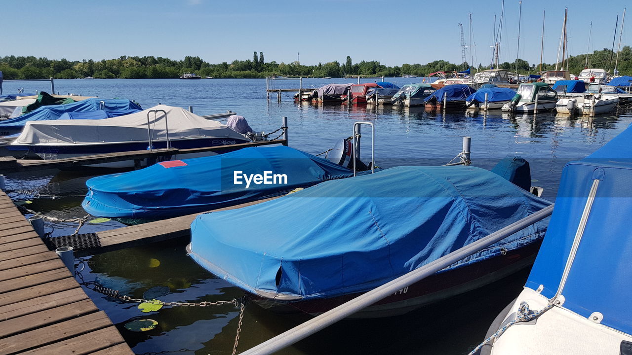 PANORAMIC VIEW OF SAILBOATS MOORED IN LAKE AGAINST BLUE SKY