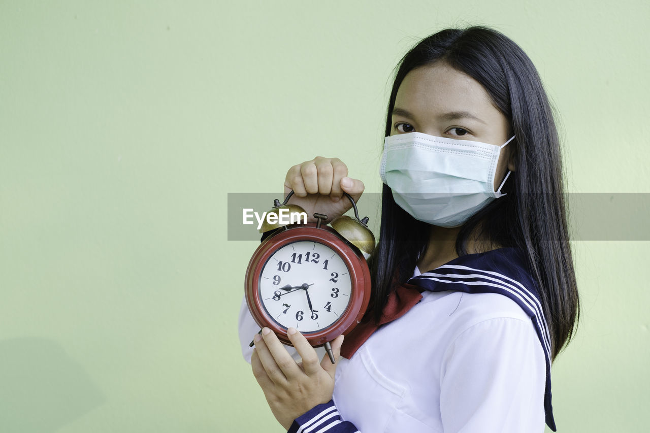 PORTRAIT OF A WOMAN HOLDING CLOCK