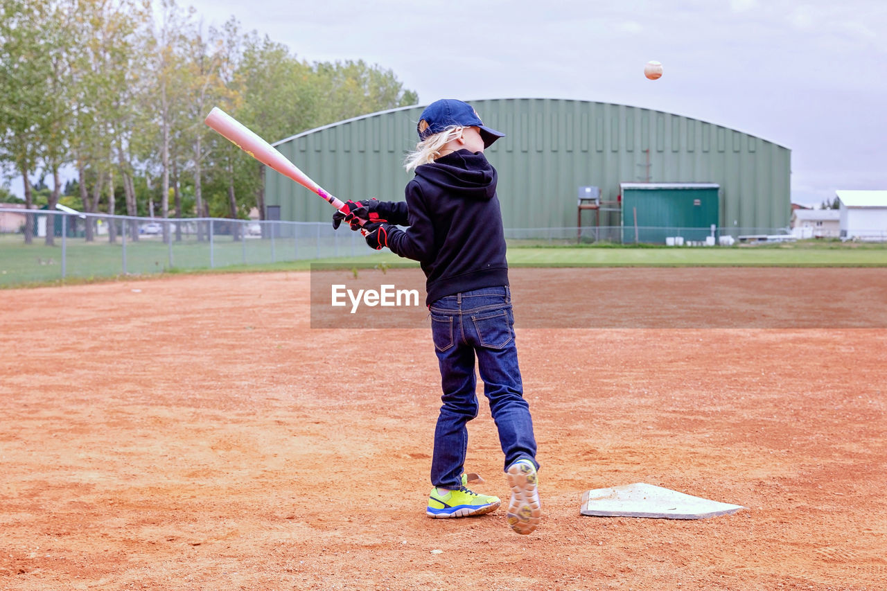 Full length of girl playing baseball at field