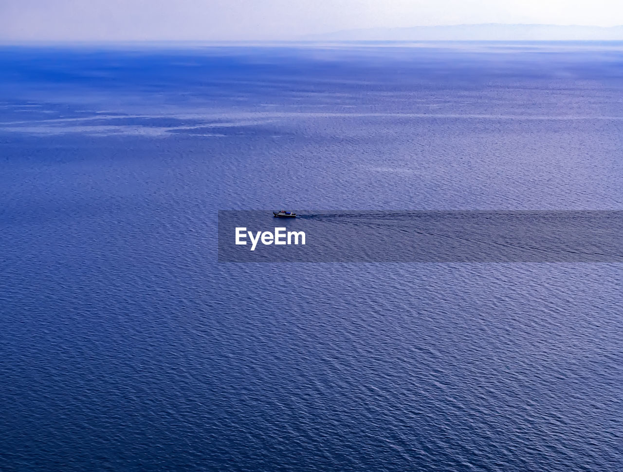 View of a horizon with a small ship over the large body of water. panoramic blue waterscape.