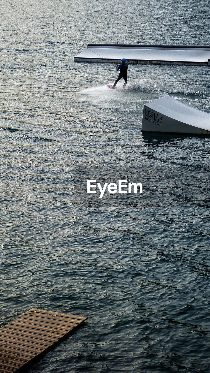 HIGH ANGLE VIEW OF MEN SWIMMING IN LAKE