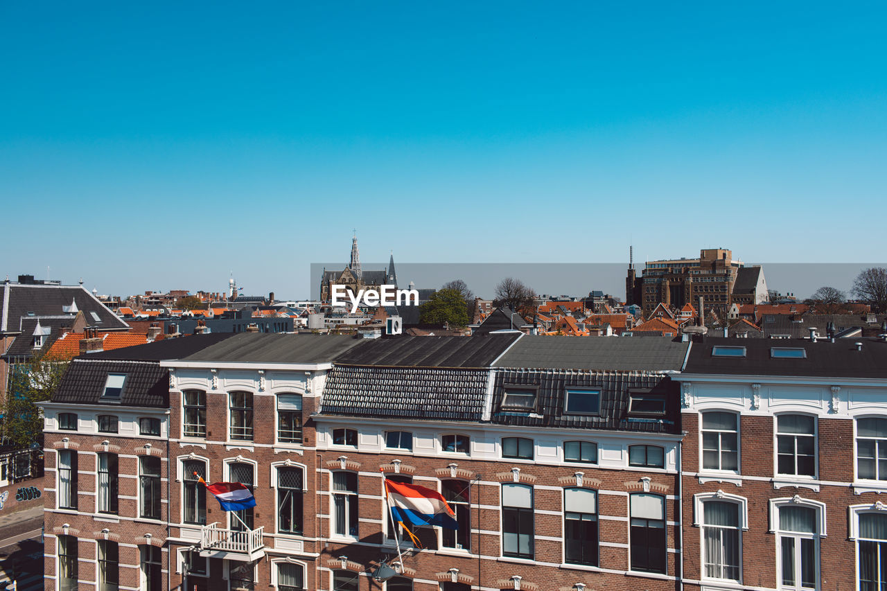 Buildings in city against clear blue sky