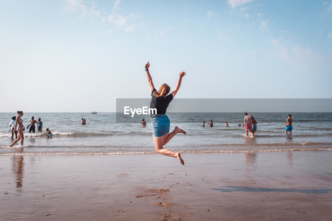 People enjoying at beach against sky