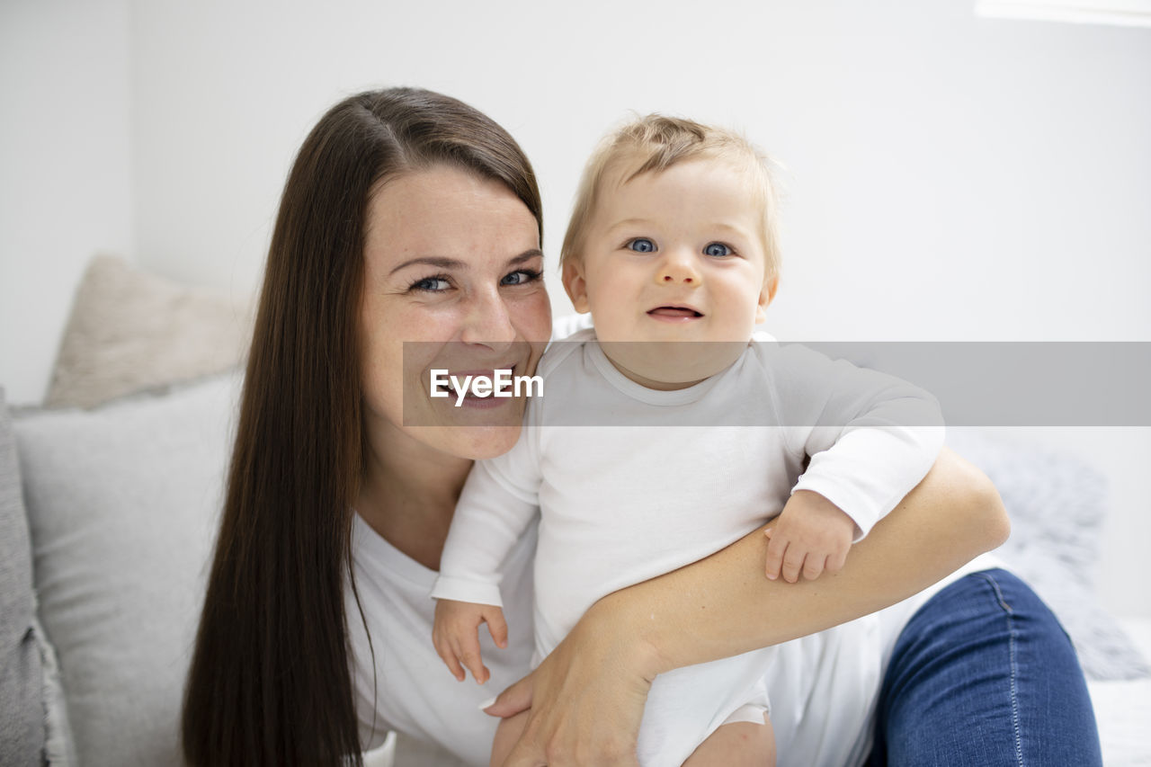 portrait of happy family sitting on bed at home