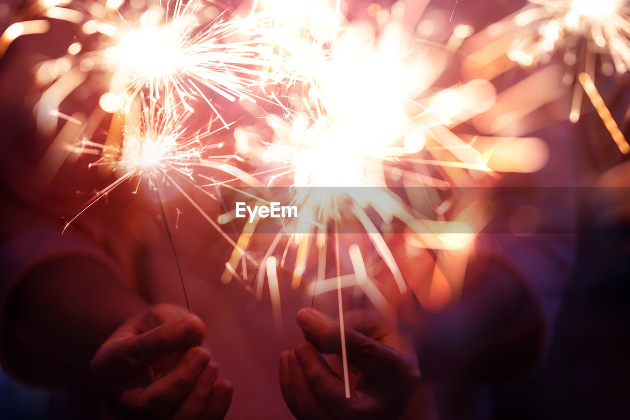 Midsection of woman holding sparklers at night