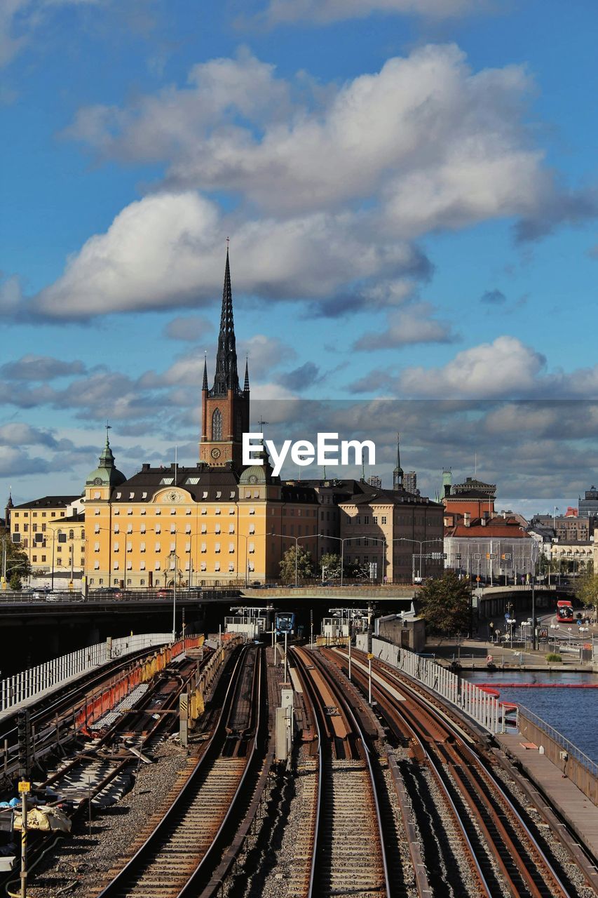 Railroad tracks amidst buildings in city against sky