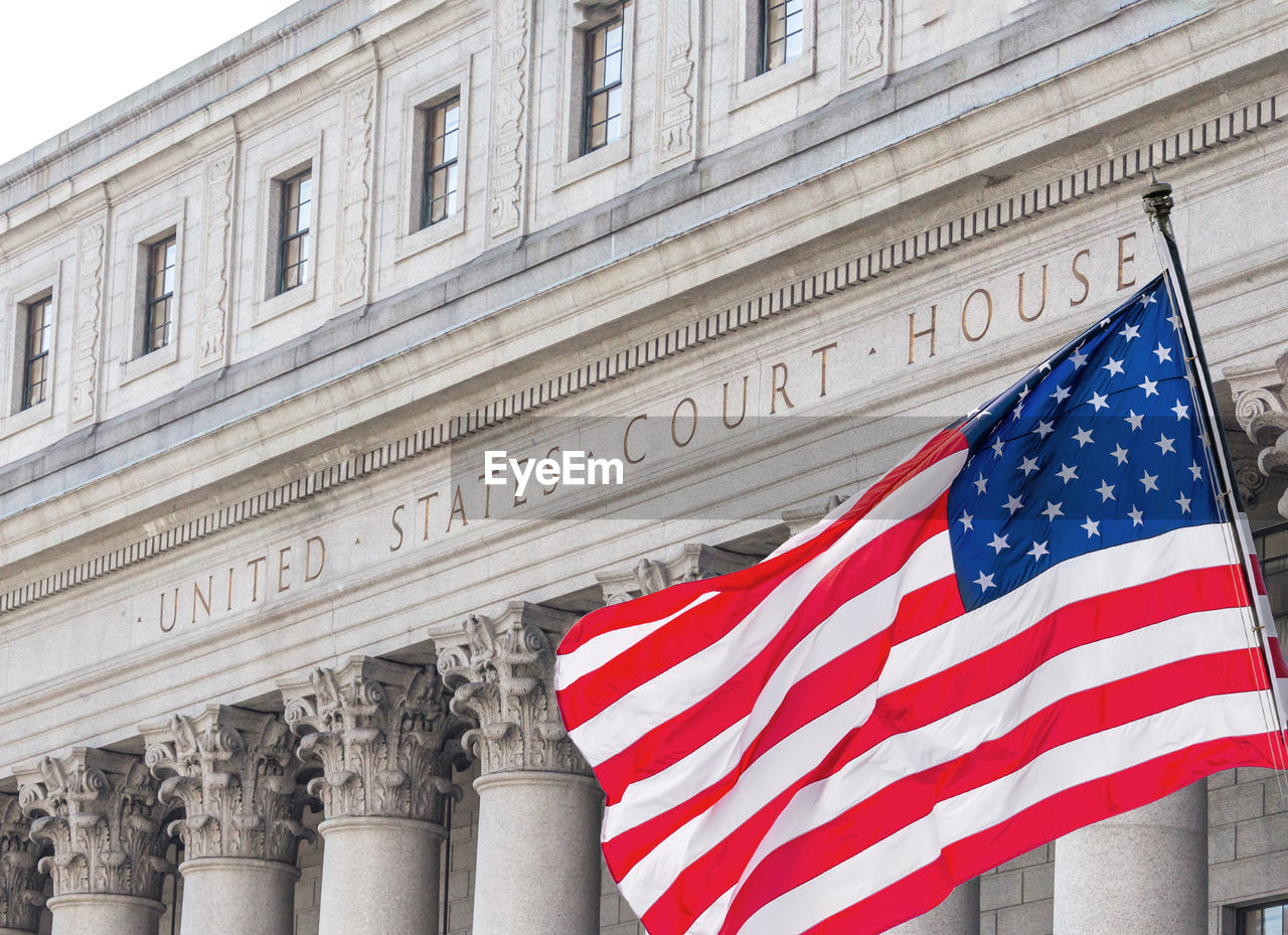American flag waving in the wind in front of united states court house in new york