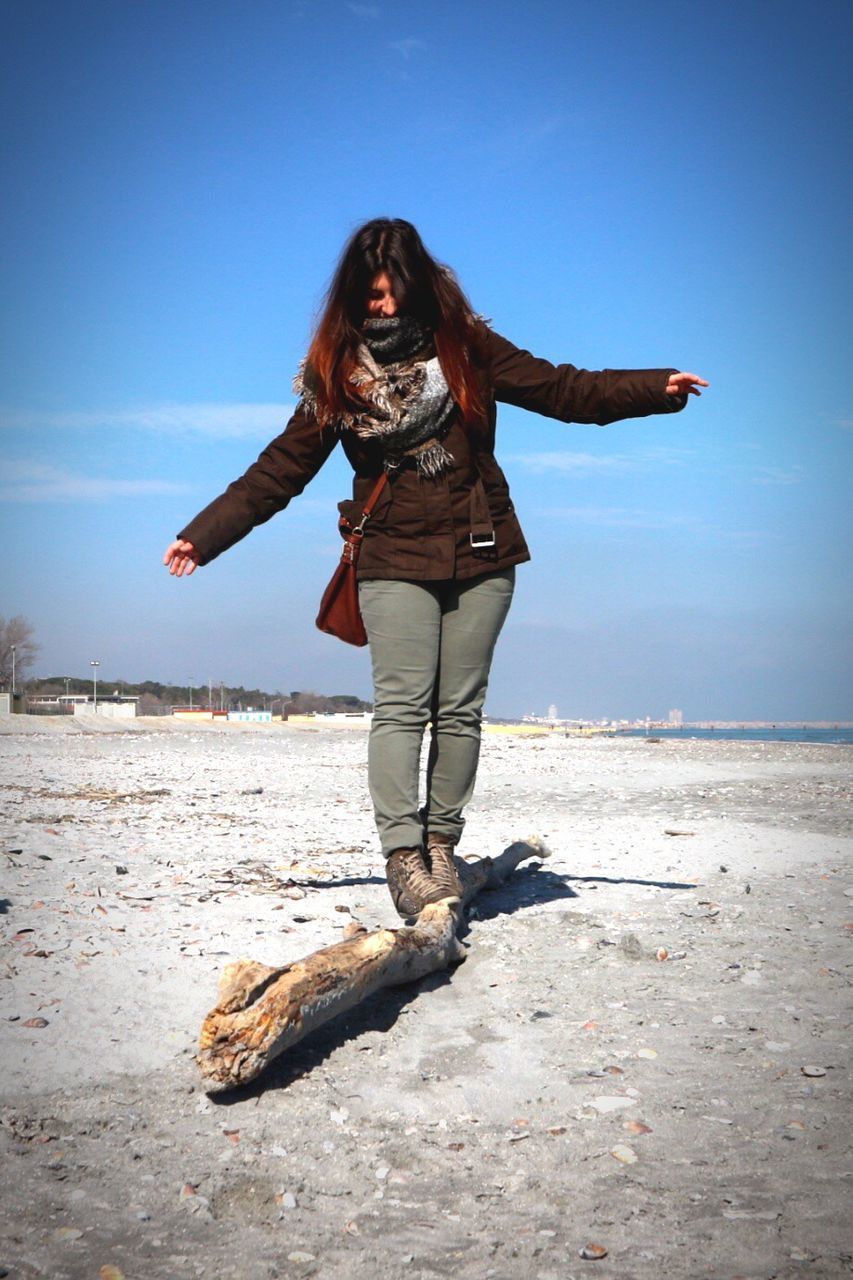 FULL LENGTH OF YOUNG WOMAN STANDING AT BEACH