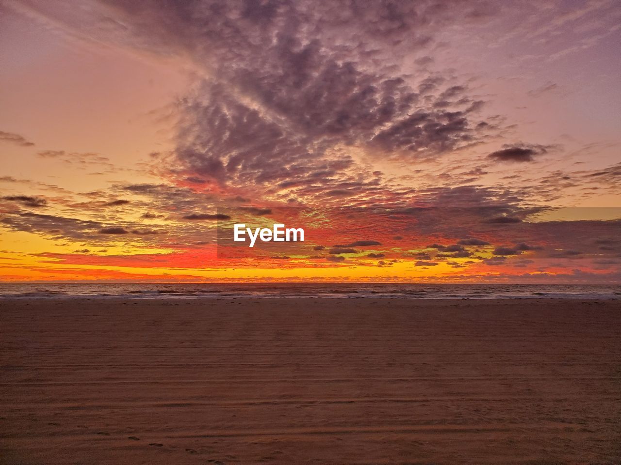 Scenic view of sea against dramatic sky during sunset