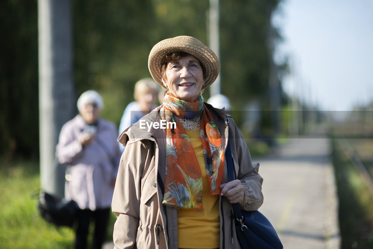 Portrait of smiling senior woman wearing summer hat traveling on during covid-19 pandemic