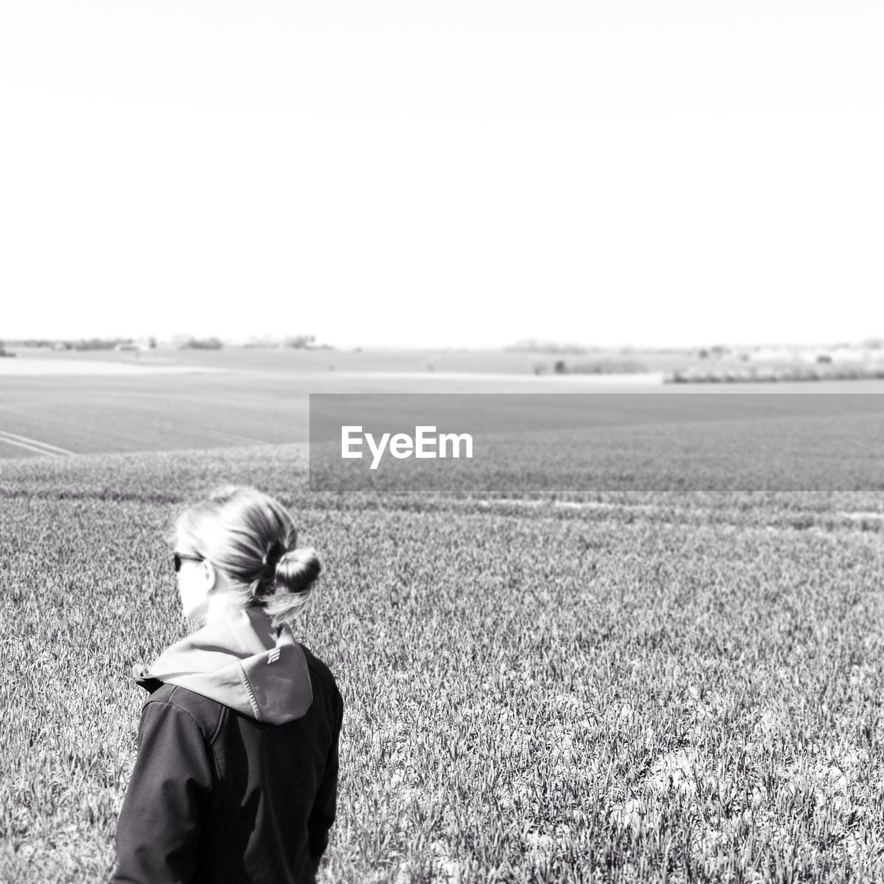 YOUNG WOMAN STANDING ON GRASSY FIELD