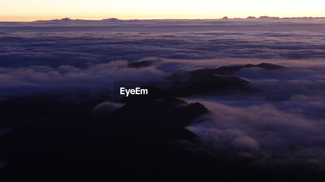 Scenic view of clouds on mountaintop during sunrise