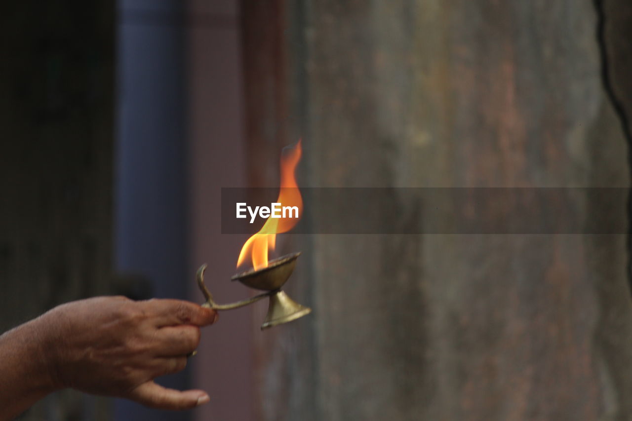 Cropped hand of man holding burning diya during religious ceremony