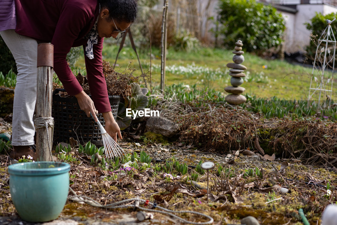 Woman cleaning while standing by plants