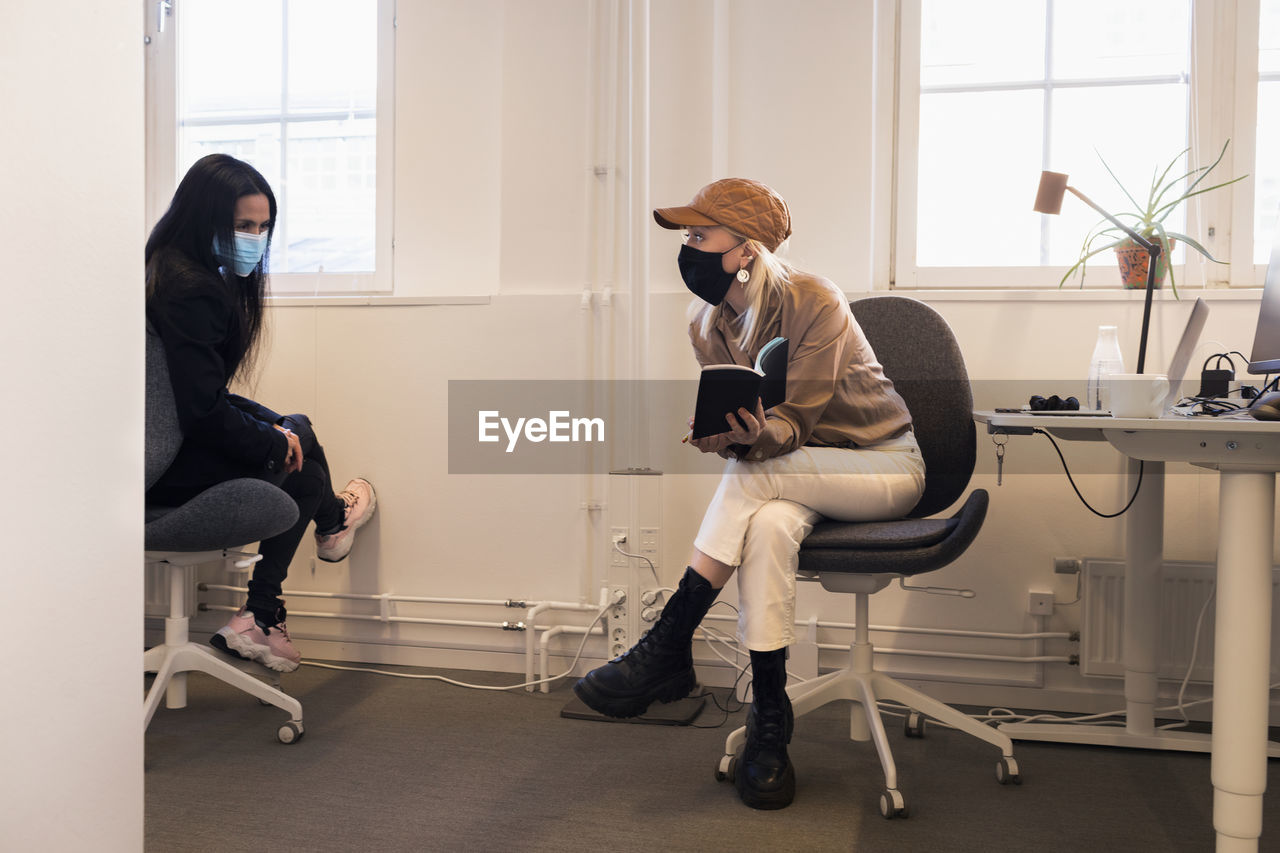 Women in face masks talking in office