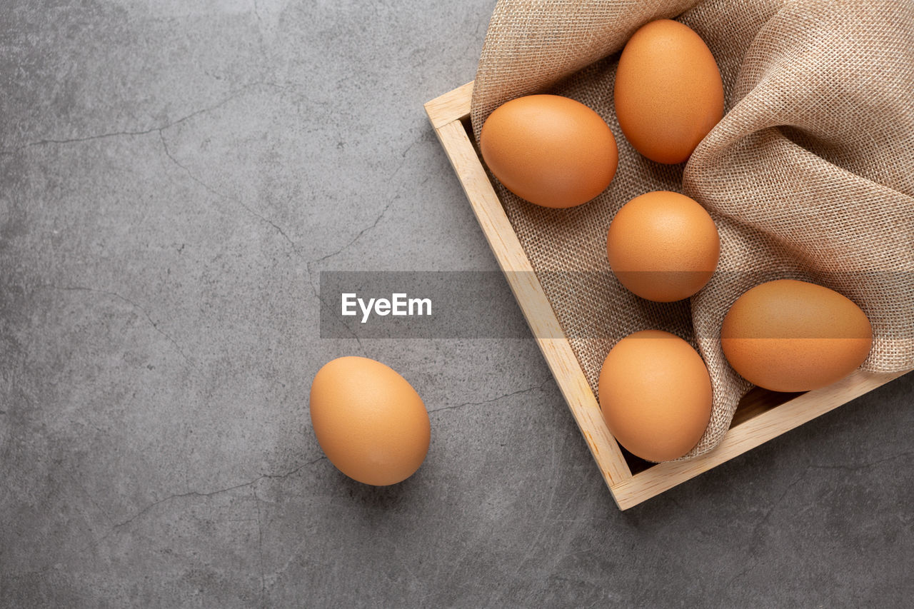 Chicken eggs on the wooden tray on the black table. top view.