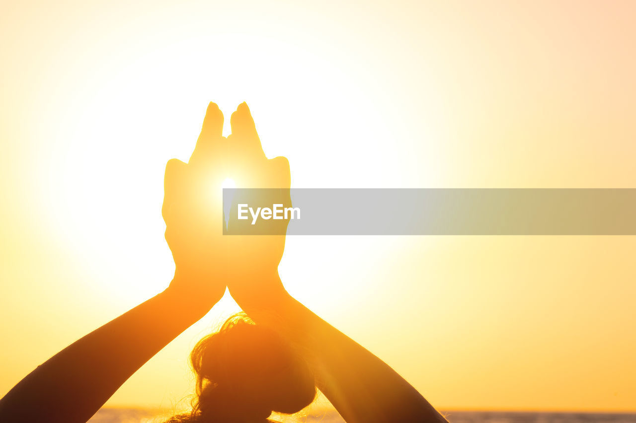 Close-up yoga woman meditating at serene sunset or sunrise on the beach. the girl relaxes in the