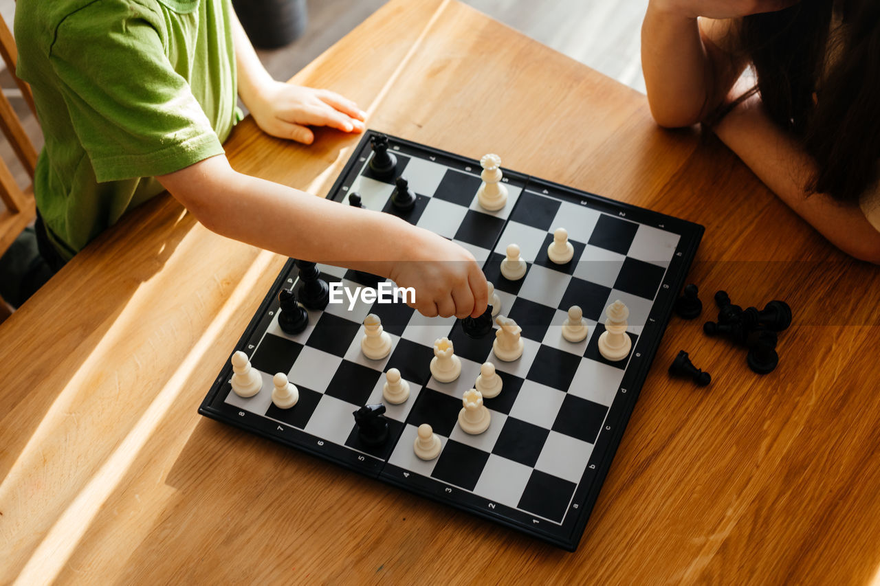 HIGH ANGLE VIEW OF PEOPLE PLAYING ON TABLE AT HOME