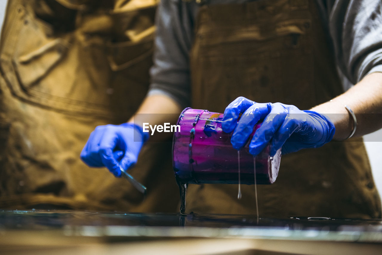 Female resin artist pouring resin tint messily