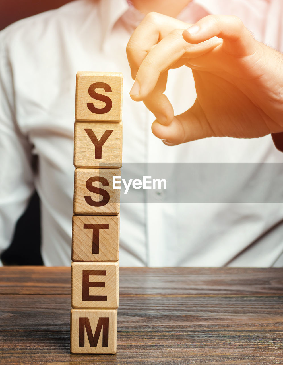 Men knocks down wooden block tower with word system. system destruction concept. 