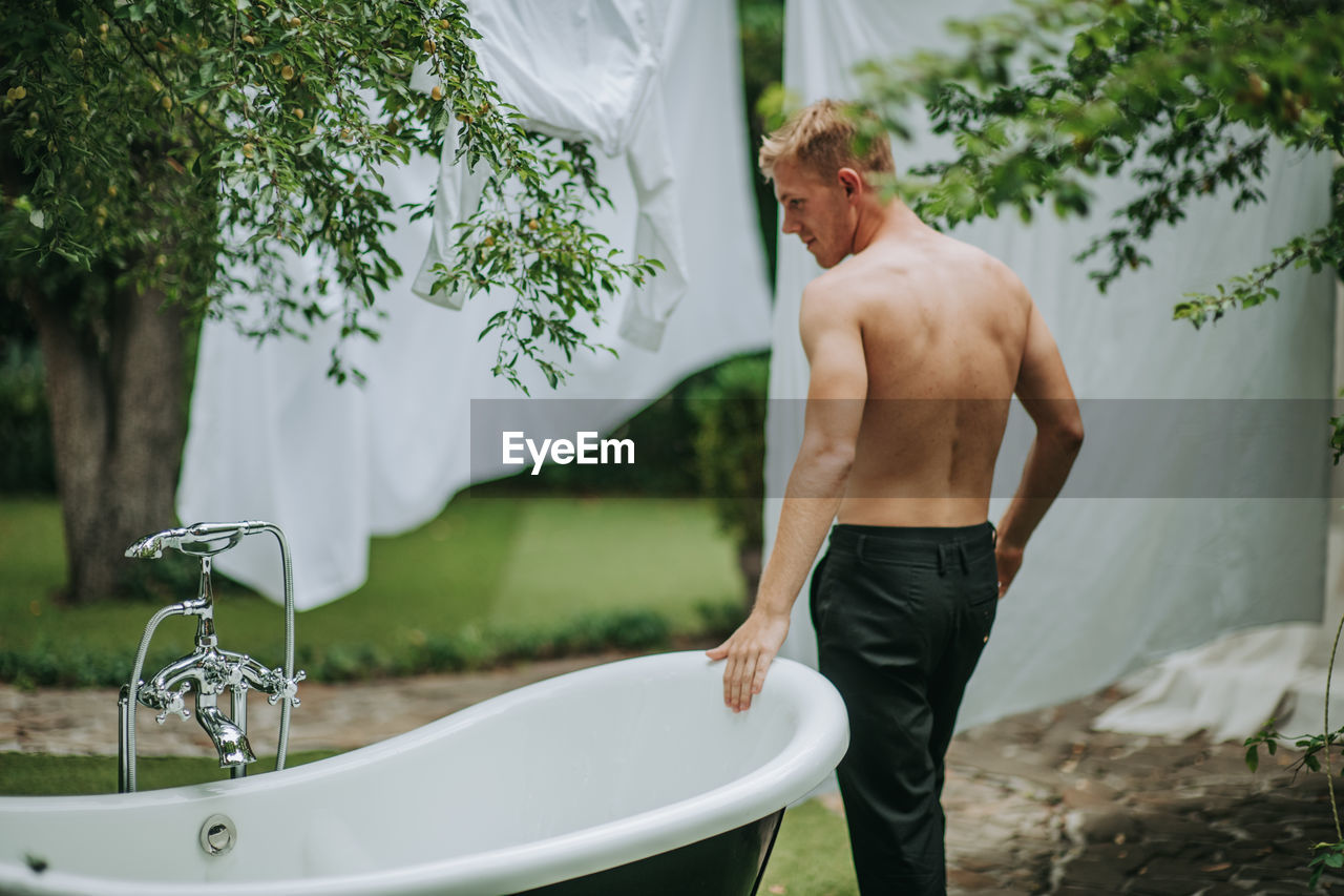 Side view of shirtless man standing in water