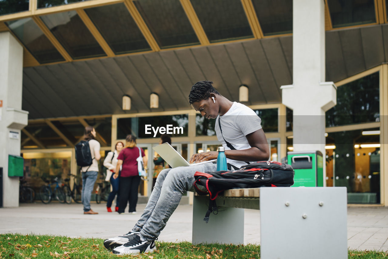 Male college student e-learning on laptop in campus