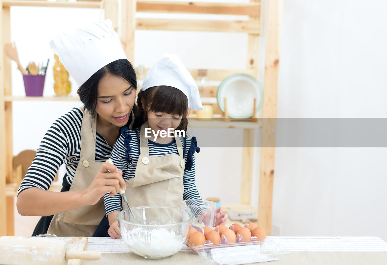 Mother and daughter preparing food in kitchen