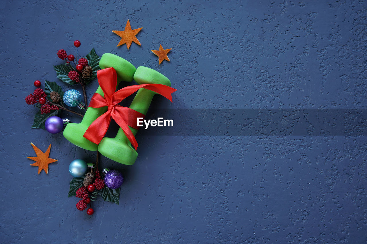 Close-up of christmas decoration with dumbbell against wall