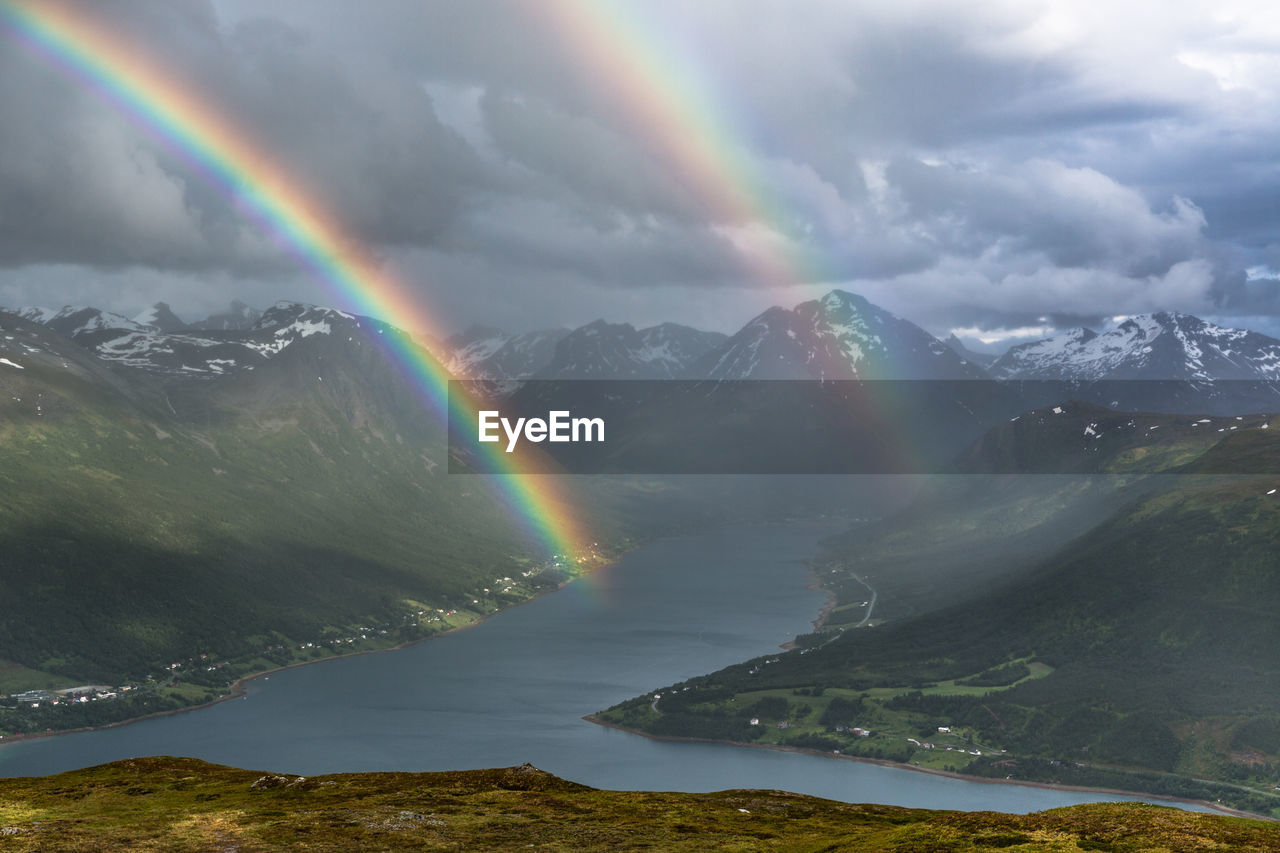 Scenic view of rainbows over lake and mountains