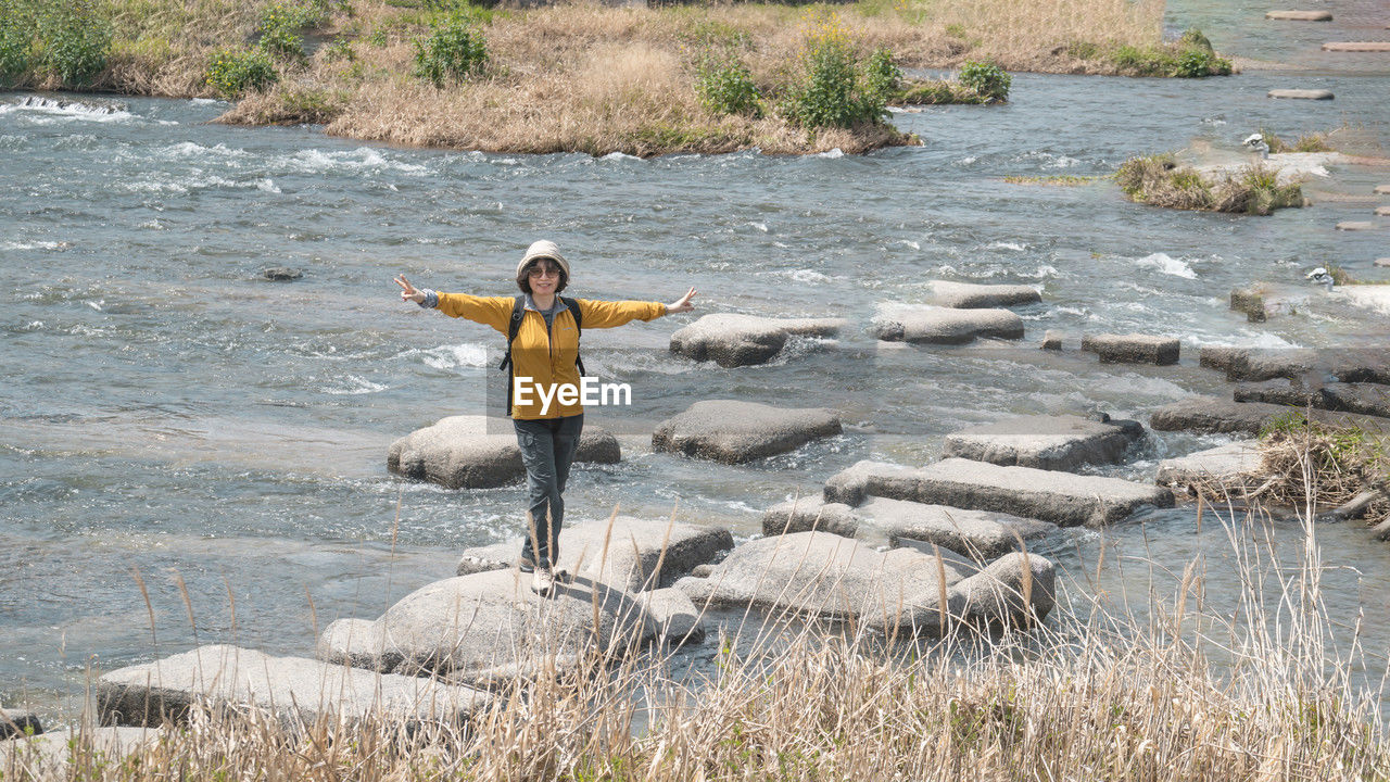 Full length of woman standing on stepping stone in the kamo river