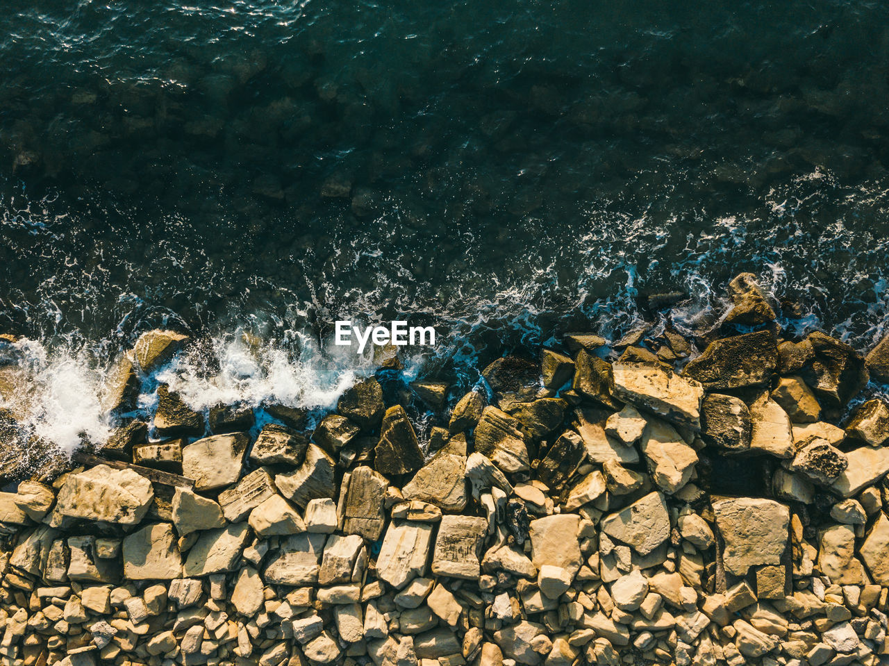 Aerial top view of sea waves hitting rocks on the beach