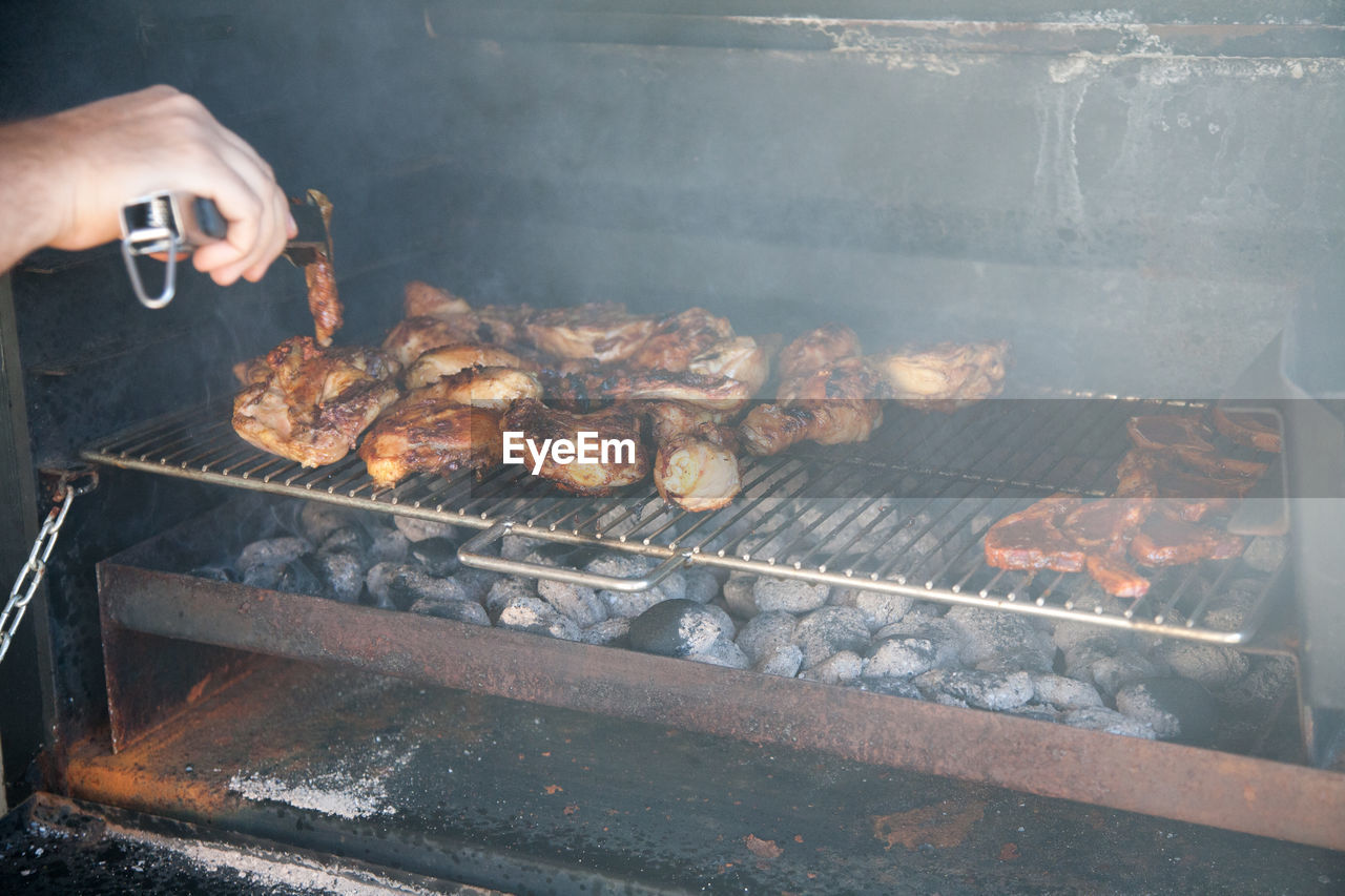 View of man preparing food on barbecue grill