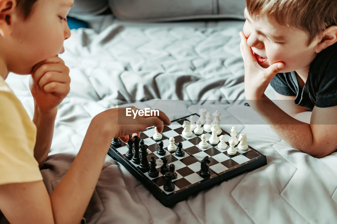 Boys play chess. children play chess at home. rivals. time without phones. it's a time together.