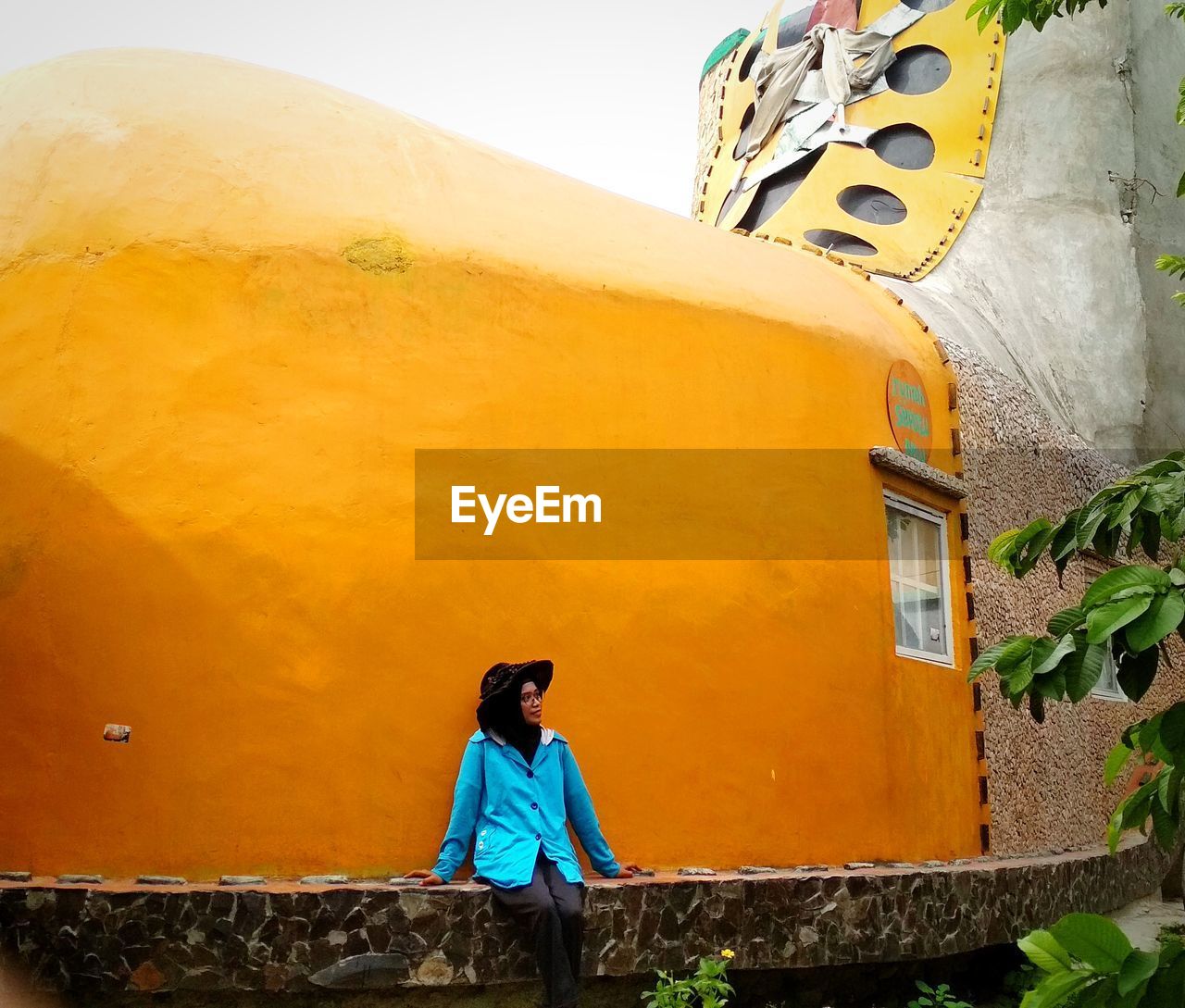 Woman sit in front of the yellow wall