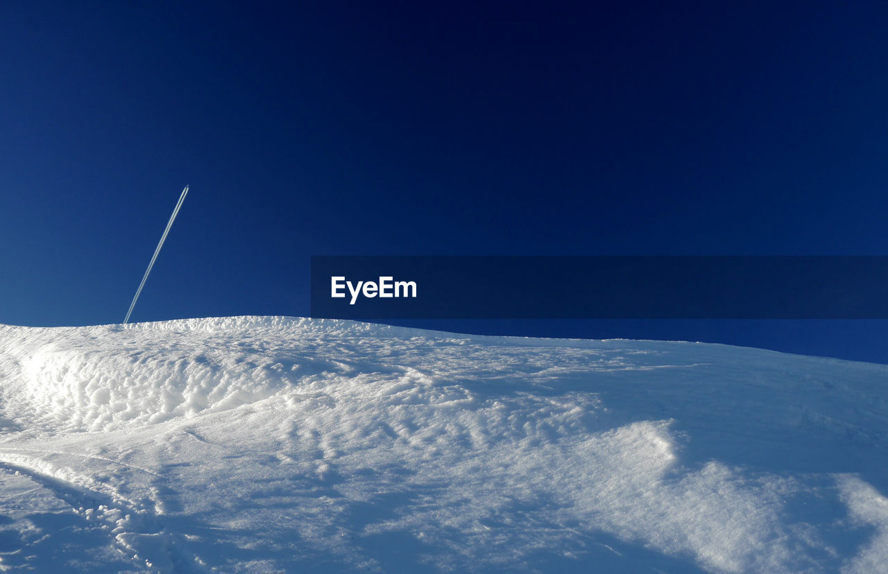 Low angle view of snowcapped mountain against blue sky