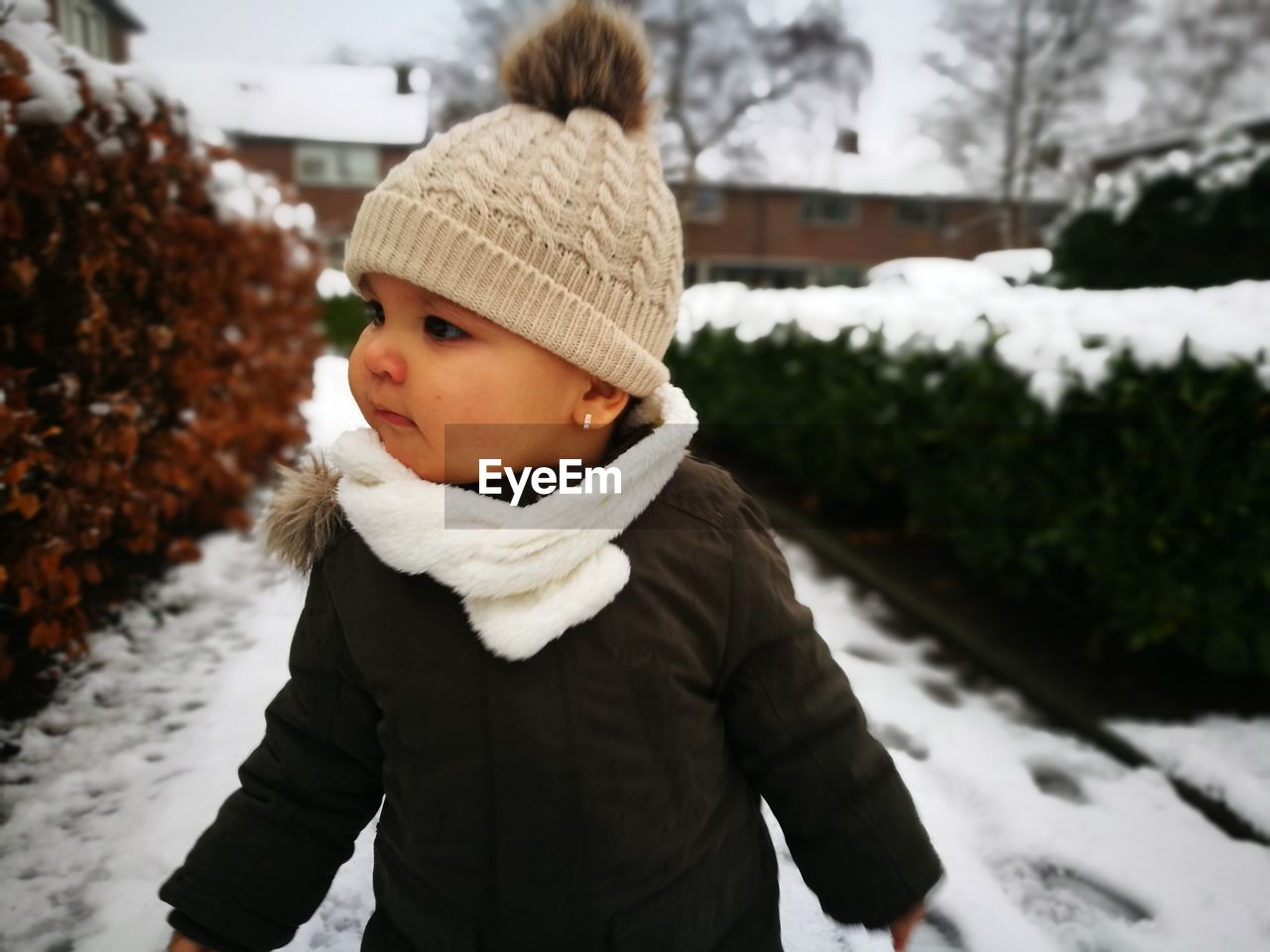 Cute baby girl wearing warm clothing while standing on snow