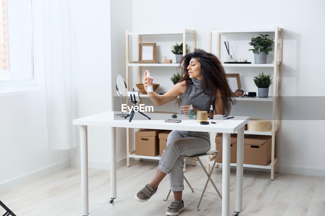 Woman filming make-up tutorial through camera at home