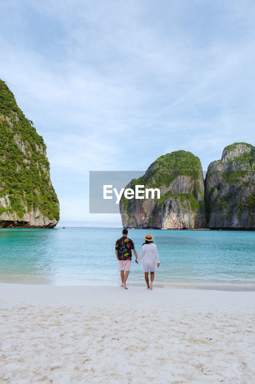 rear view of woman standing at beach against sky