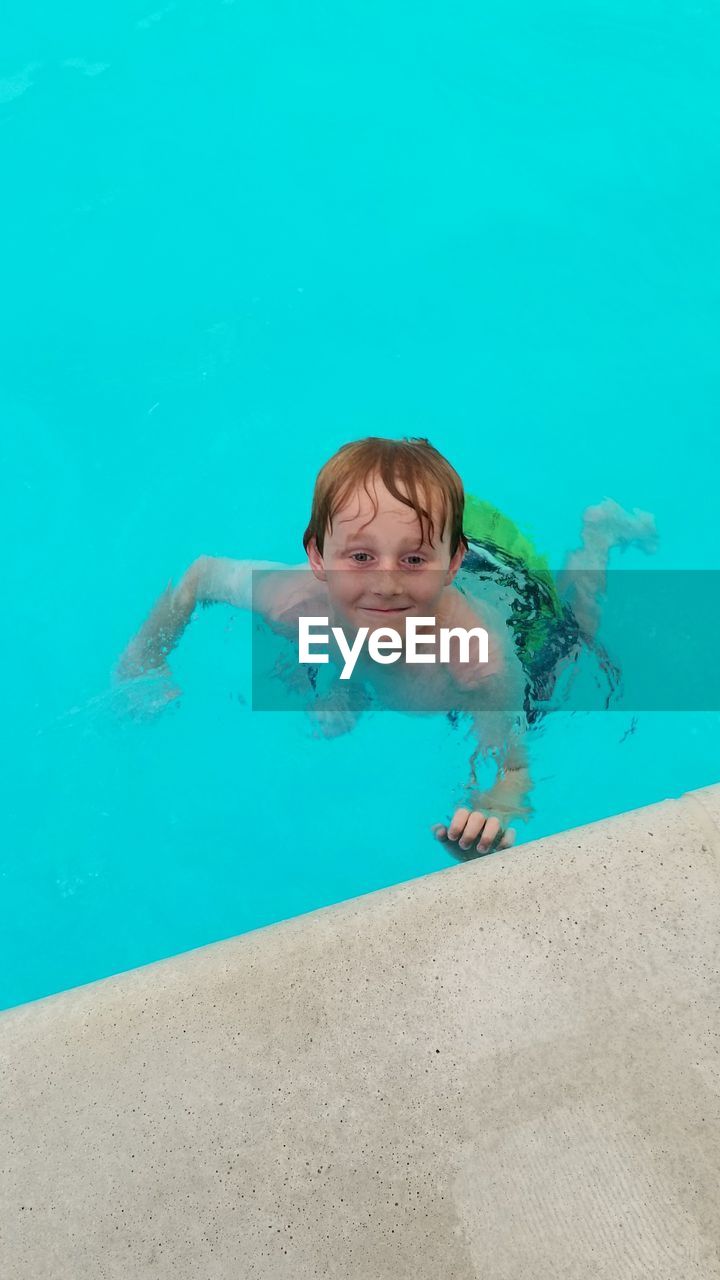 PORTRAIT OF SMILING WOMAN SWIMMING IN POOL