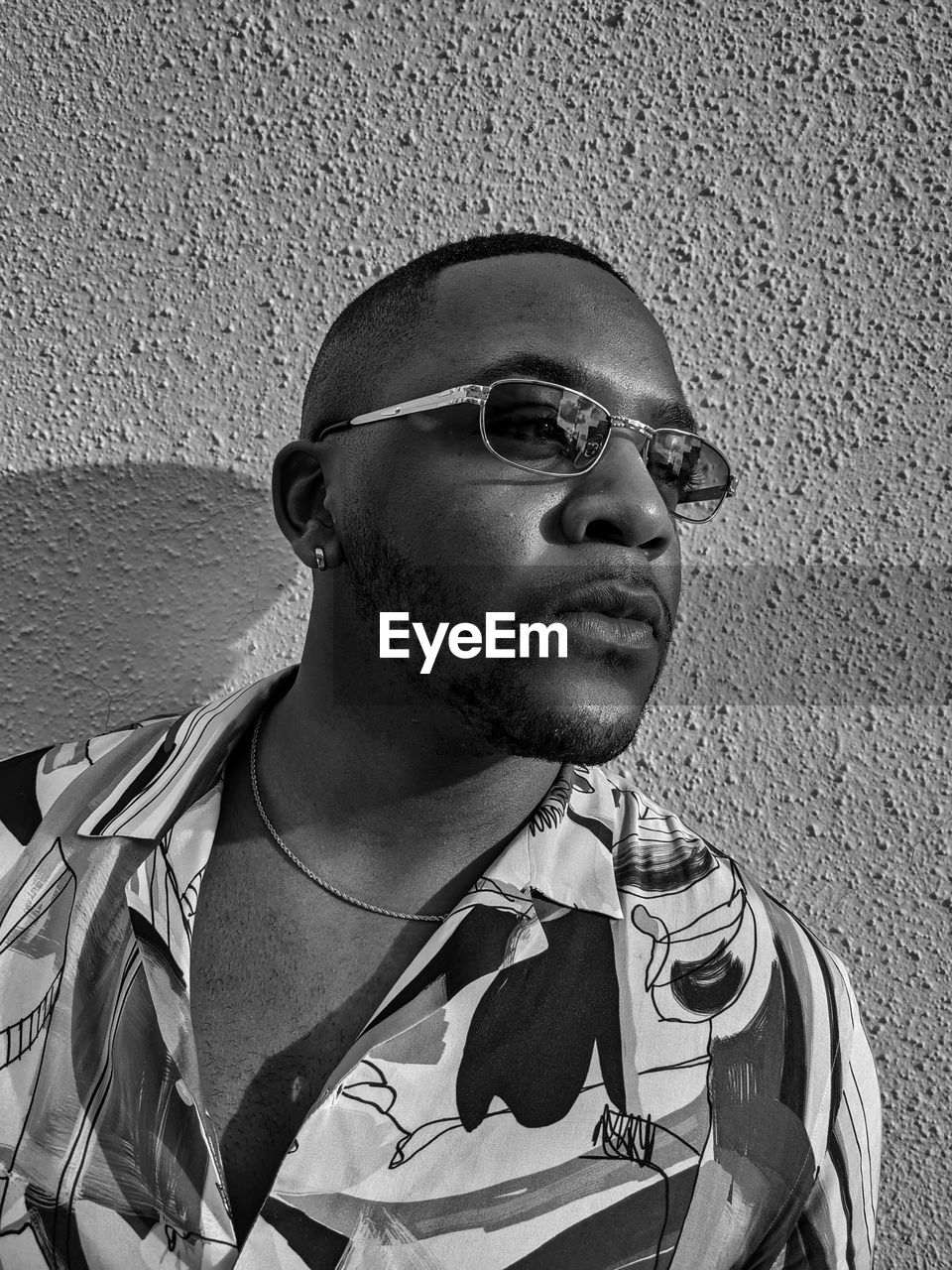 Portrait of young man wearing sunglasses against wall